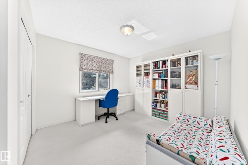 Built-in desk with integrated storage, built-in shelving units, window with patterned Roman shade, and light-colored carpeting - 209 Carmichael Close Nw, Edmonton, AB - Indoor