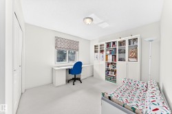 Built-in desk with integrated storage, built-in shelving units, window with patterned Roman shade, and light-colored carpeting - 