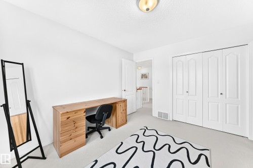 White walls with light-toned carpet, flush-mount ceiling light fixture, and white bi-fold closet doors - 209 Carmichael Close Nw, Edmonton, AB - Indoor