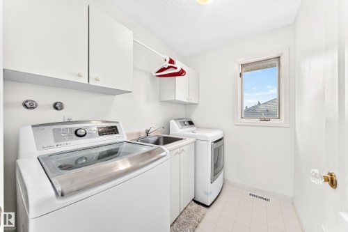 Laundry area with white cabinetry, a utility sink, and tiled flooring - 209 Carmichael Close Nw, Edmonton, AB - Indoor Photo Showing Laundry Room