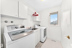 Laundry area with white cabinetry, a utility sink, and tiled flooring - 