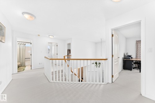 Carpeted landing featuring a wood-finish handrail, white balusters, and flush-mount lighting fixtures - 209 Carmichael Close Nw, Edmonton, AB - Indoor Photo Showing Other Room