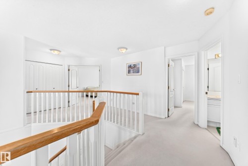 Upper-level landing with light-toned carpet flooring, white walls, and a wood and white spindle railing - 209 Carmichael Close Nw, Edmonton, AB - Indoor Photo Showing Other Room