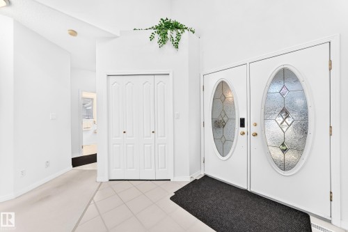 Double entry doors with decorative oval glass inserts, bi-fold closet doors, and tile flooring - 209 Carmichael Close Nw, Edmonton, AB - Indoor Photo Showing Other Room