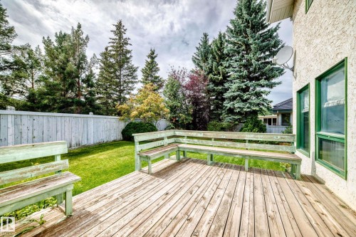 Expansive wood deck with built-in bench seating, surrounded by a manicured lawn and mature trees - 209 Carmichael Close Nw, Edmonton, AB - Outdoor With Deck Patio Veranda