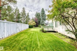 Expansive lawn area bordered by a tall white fence and mature trees - 