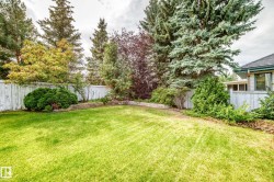 Expansive rear yard featuring a manicured lawn, established landscaping, privacy fencing, and mature trees - 