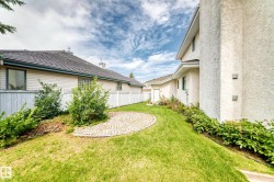 Expansive green space featuring a circular paver patio, established landscaping, and a privacy fence - 