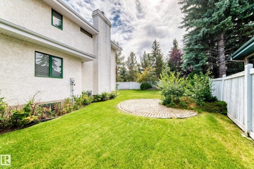 Exterior stucco finish, prominent chimney feature, circular paver patio, established landscaping, and a perimeter fence - 209 Carmichael Close Nw, Edmonton, AB - Outdoor