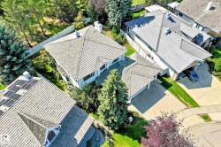Pitched rooflines, attached two-car garage, concrete driveway, and mature landscaping - 