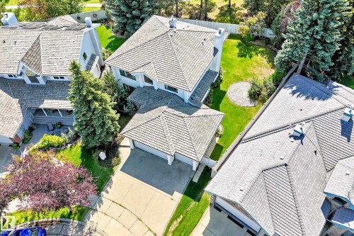 White multi-story residence with a gray shingle roof, attached two-car garage, expansive concrete driveway, and mature landscaping - 209 Carmichael Close Nw, Edmonton, AB - Outdoor