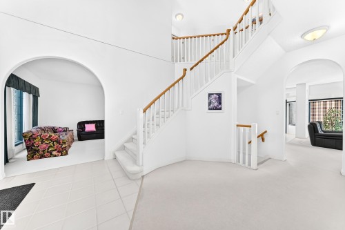 Grand two-story foyer featuring a curved staircase with wood handrails and white balusters - 209 Carmichael Close Nw, Edmonton, AB - Indoor Photo Showing Other Room