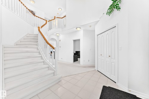 Curved staircase with wood-finish handrails, white balusters, and carpeted treads - 209 Carmichael Close Nw, Edmonton, AB - Indoor Photo Showing Other Room