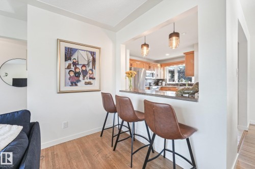 Kitchen pass-through with stone countertop and built-in breakfast bar - 16613 90 Avenue Nw, Edmonton, AB - Indoor Photo Showing Dining Room