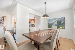 Light-toned wood-finish flooring, a contemporary pendant light fixture, and a pass-through bar with seating - 