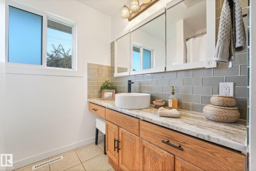 Vanity with wood-finish cabinetry, stone countertop, vessel sink, and subway tile backsplash - 16613 90 Avenue Nw, Edmonton, AB - Indoor Photo Showing Bathroom