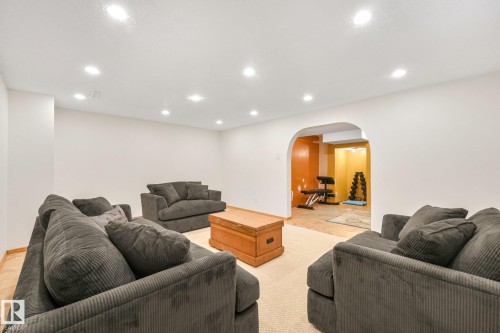 Recessed ceiling lighting illuminates a spacious room featuring an arched entryway to a separate area with varied wall colors - 16613 90 Avenue Nw, Edmonton, AB - Indoor Photo Showing Basement
