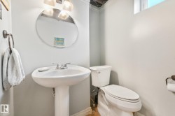 Pedestal sink with chrome faucet, round wall mirror, and overhead vanity lighting - 