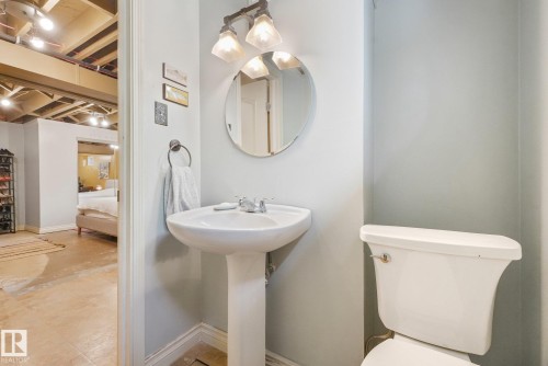 Pedestal sink with chrome faucet, wall-mounted mirror, and vanity light fixture - 16613 90 Avenue Nw, Edmonton, AB - Indoor Photo Showing Bathroom