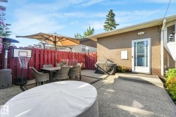 Expansive concrete patio area with a red privacy fence and exterior door access - 