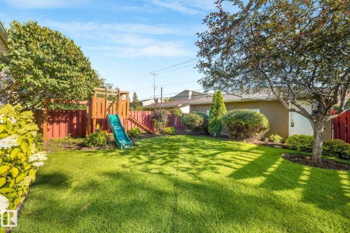 Expansive lawn area with mature trees, established shrubbery, and a wood privacy fence - 16613 90 Avenue Nw, Edmonton, AB - Outdoor