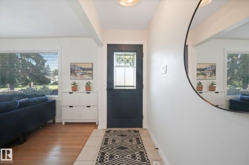 Entryway featuring a dark paneled door with leaded glass, tile flooring, and a large window with horizontal blinds - 16613 90 Avenue Nw, Edmonton, AB - Indoor Photo Showing Other Room