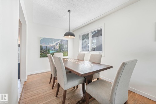 Wood-finish flooring with a chevron pattern, white painted walls, and a window with horizontal blinds - 16613 90 Avenue Nw, Edmonton, AB - Indoor Photo Showing Dining Room