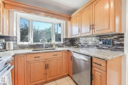 Bay window, granite countertops, wood cabinetry, tile backsplash, stainless steel dishwasher - 