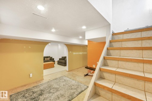 Staircase with tile risers and wood treads, recessed lighting, and an arched doorway leading to a separate area - 16613 90 Avenue Nw, Edmonton, AB - Indoor