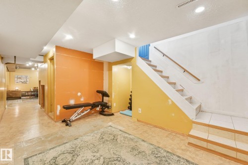 Staircase with wood handrail, recessed lighting, and tile flooring - 16613 90 Avenue Nw, Edmonton, AB - Indoor