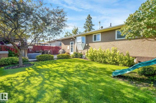 Expansive backyard featuring a manicured lawn, established trees, a concrete patio, and a privacy fence - 16613 90 Avenue Nw, Edmonton, AB - Outdoor