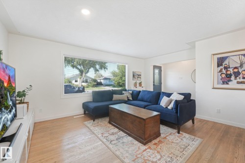 Bright living space featuring wood-finish flooring, a large window with blinds, and recessed lighting - 16613 90 Avenue Nw, Edmonton, AB - Indoor Photo Showing Living Room