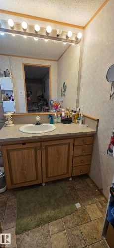 Vanity with wood-finish cabinetry, integrated sink, and laminate countertop - #56 4202 45 St, Wetaskiwin, AB - Indoor Photo Showing Bathroom