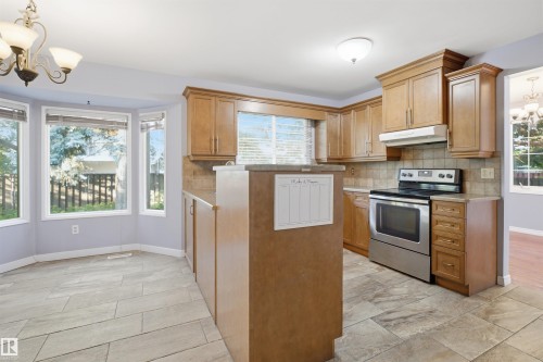 Kitchen featuring wood cabinetry, stainless steel range, tiled backsplash, and tile flooring - 3432 Hill View Crescent Nw, Edmonton, AB - Indoor Photo Showing Kitchen