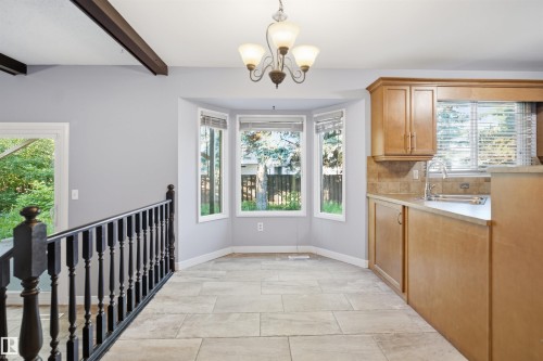 Recessed bay window, tile flooring, light wood-finish cabinetry, built-in sink, and a multi-light chandelier - 3432 Hill View Crescent Nw, Edmonton, AB - Indoor
