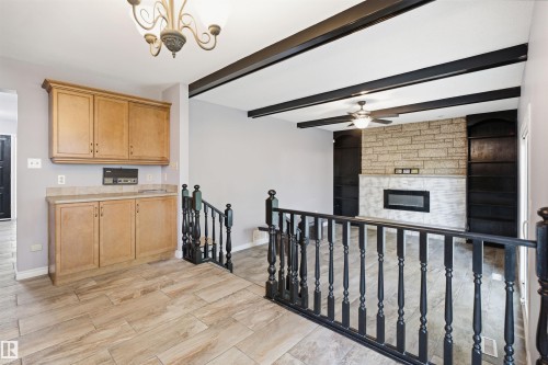 Built-in cabinetry with counter space, tile flooring, open-beam ceiling, stone-clad fireplace, and integrated shelving - 3432 Hill View Crescent Nw, Edmonton, AB - Indoor