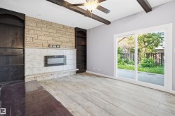 Stone-clad fireplace with an integrated electric insert, flanked by built-in shelving, and exposed ceiling beams - 