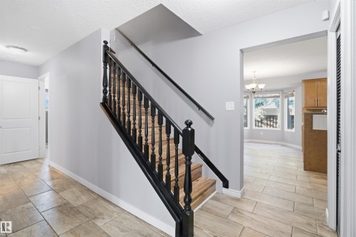 Wood-finish tile flooring, black wood staircase with balusters, and a bay window in the adjacent space - 3432 Hill View Crescent Nw, Edmonton, AB - Indoor Photo Showing Other Room