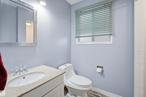 White vanity with an integrated sink, polished chrome faucet, stone-finish countertop, and a framed wall mirror - 3432 Hill View Crescent Nw, Edmonton, AB - Indoor Photo Showing Bathroom