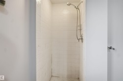 White tiled shower enclosure with a chrome shower head and fixture - 