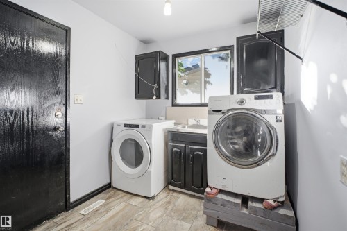 Laundry area with wood-finish flooring, dark cabinetry, and a window - 3432 Hill View Crescent Nw, Edmonton, AB - Indoor Photo Showing Laundry Room