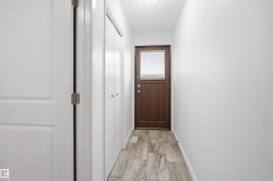 Wood-finish flooring, white walls, and a brown door with an upper window - 