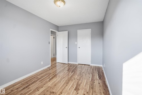 Wood-finish flooring, light gray wall color, white interior doors, and a ceiling-mounted light fixture - 3432 Hill View Crescent Nw, Edmonton, AB - Indoor Photo Showing Other Room