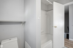 White bathtub with a shower surround and wall-mounted hook - 