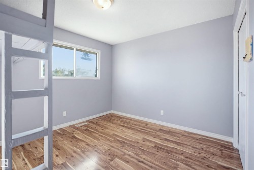 Wood-finish flooring, light gray wall paint, and a white ceiling with a flush-mount light fixture - 3432 Hill View Crescent Nw, Edmonton, AB - Indoor Photo Showing Other Room