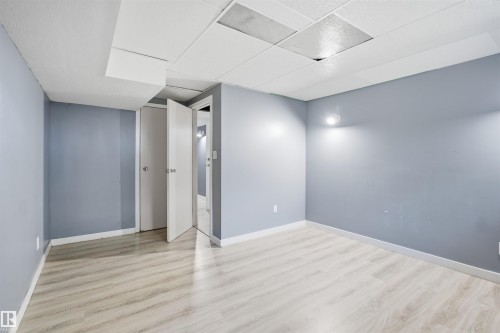 Light-toned wood-finish flooring, two white doors with round knobs, and wall-mounted lighting - 3432 Hill View Crescent Nw, Edmonton, AB - Indoor Photo Showing Other Room