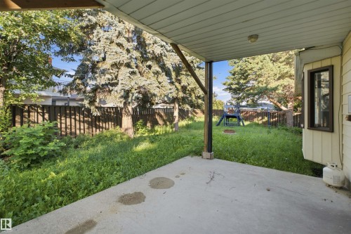 Covered concrete patio overlooking a fenced backyard with mature trees - 3432 Hill View Crescent Nw, Edmonton, AB - Outdoor With Deck Patio Veranda
