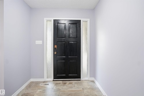 Front entry with a paneled door, textured glass sidelights, and tile flooring - 3432 Hill View Crescent Nw, Edmonton, AB - Indoor Photo Showing Other Room