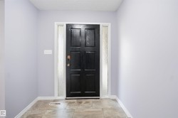 Front entry with a paneled door, textured glass sidelights, and tile flooring - 
