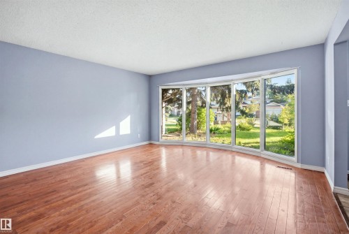 Curved bay window, wood-finish flooring, white trim, and light blue walls - 3432 Hill View Crescent Nw, Edmonton, AB - Indoor Photo Showing Other Room